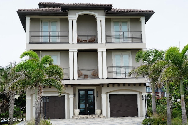 mediterranean / spanish home with a garage, a balcony, and french doors