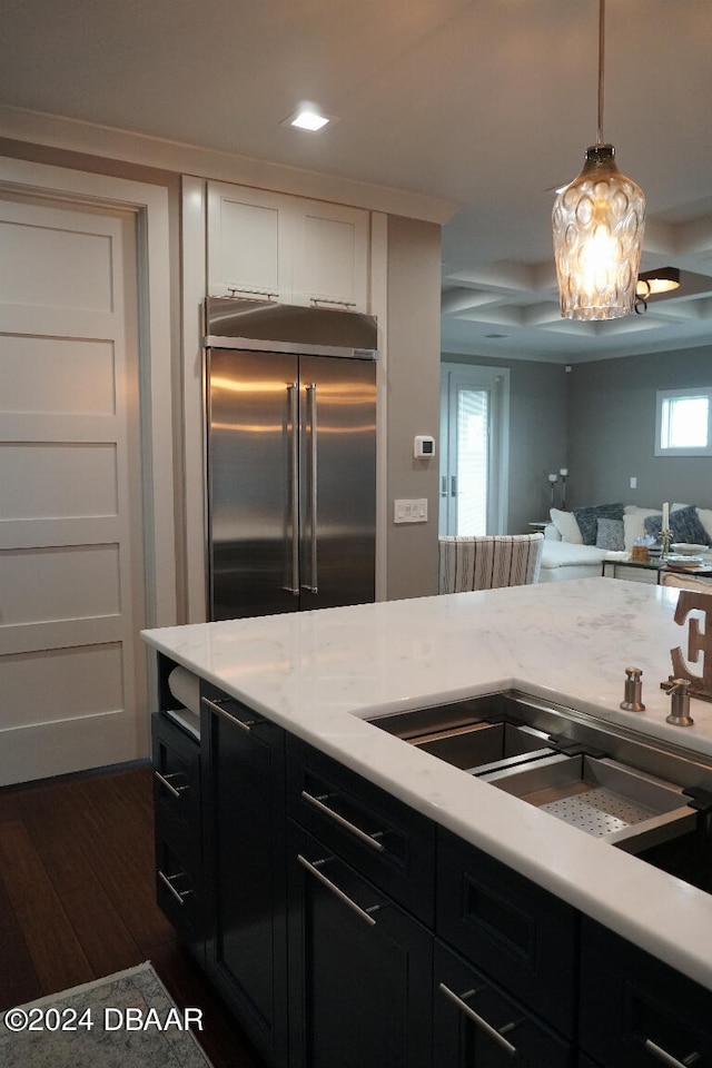 kitchen featuring plenty of natural light, stainless steel built in refrigerator, dark wood-type flooring, and hanging light fixtures