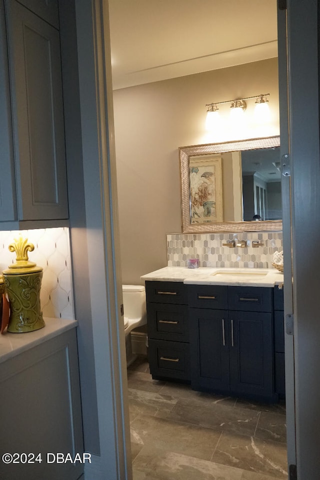 bathroom with vanity, toilet, and backsplash