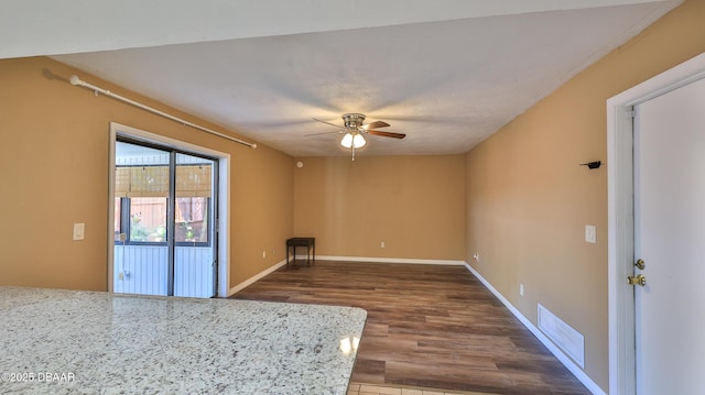 spare room featuring baseboards, visible vents, a ceiling fan, and dark wood-type flooring