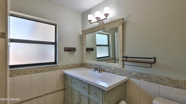 bathroom with a wealth of natural light, toilet, and tile walls