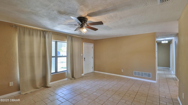 empty room featuring a textured ceiling, visible vents, ceiling fan, and baseboards
