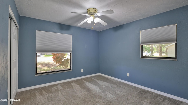 carpeted empty room with a ceiling fan, a textured ceiling, and baseboards