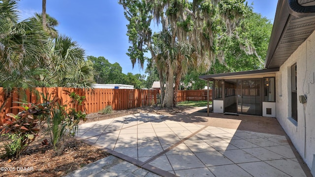 view of patio featuring a fenced backyard and a sunroom
