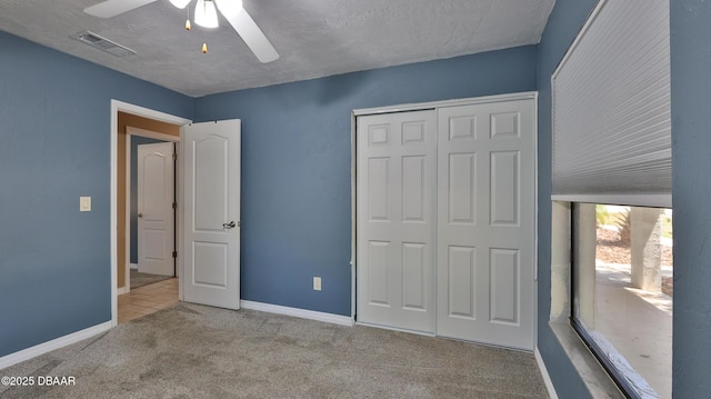 unfurnished bedroom with carpet flooring, a closet, a ceiling fan, visible vents, and baseboards