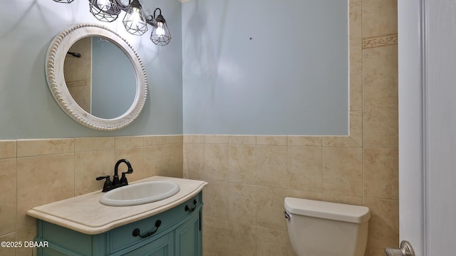 bathroom featuring vanity, toilet, and tile walls