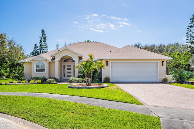 view of front of home featuring decorative driveway, roof with shingles, stucco siding, an attached garage, and a front yard