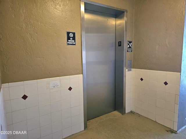 bathroom with elevator and concrete flooring