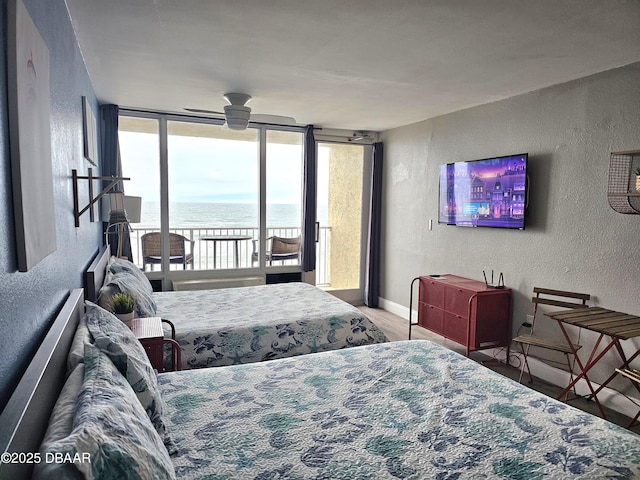 bedroom featuring access to outside, floor to ceiling windows, ceiling fan, and hardwood / wood-style floors