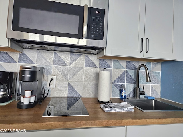 kitchen with white cabinets, tasteful backsplash, butcher block countertops, and sink