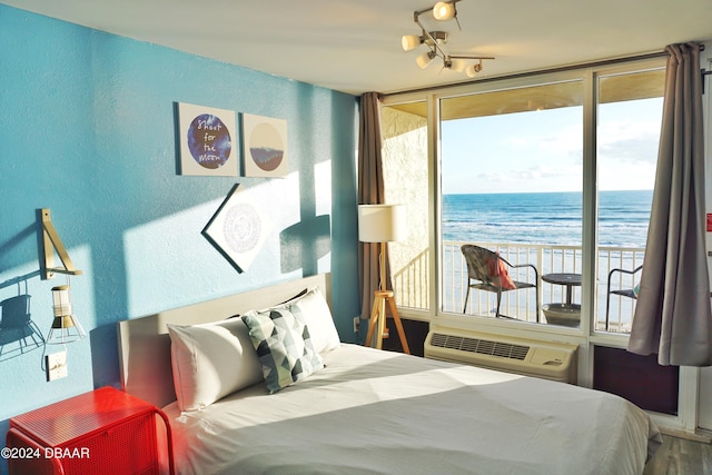 bedroom featuring a wall mounted air conditioner, a notable chandelier, floor to ceiling windows, and a water view