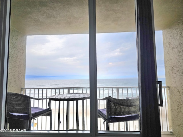 balcony with a water view and a view of the beach