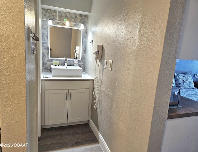 bathroom with hardwood / wood-style flooring, vanity, and backsplash