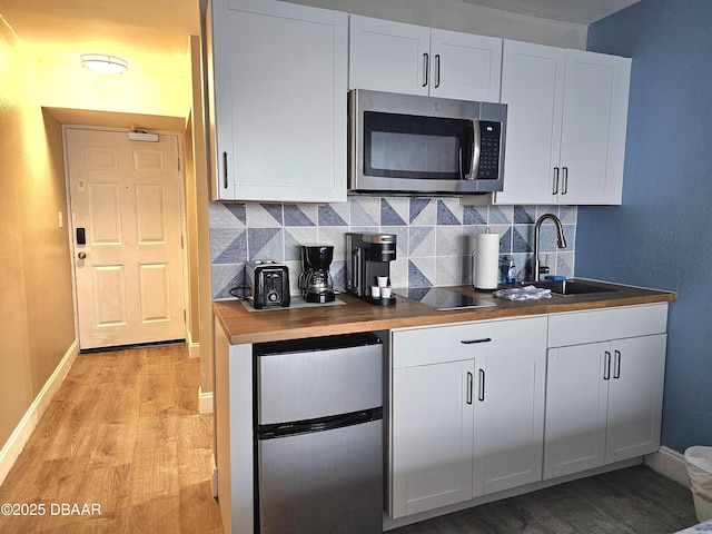 kitchen featuring butcher block countertops, white cabinetry, light hardwood / wood-style flooring, and stainless steel appliances