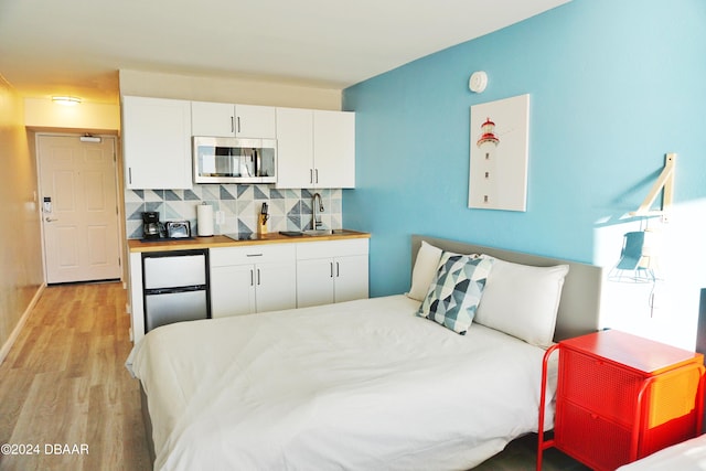 bedroom with sink and light hardwood / wood-style flooring