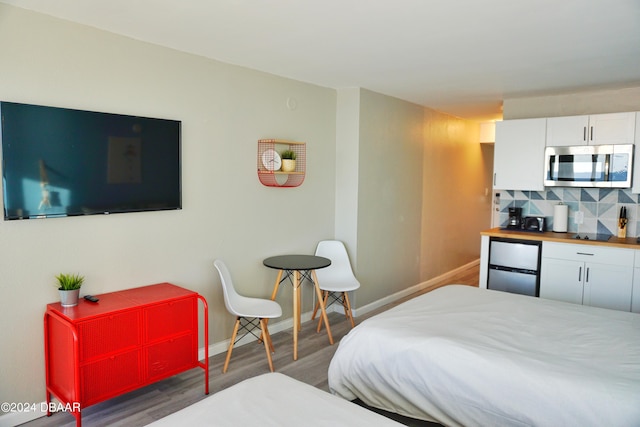 bedroom with stainless steel fridge and dark hardwood / wood-style floors