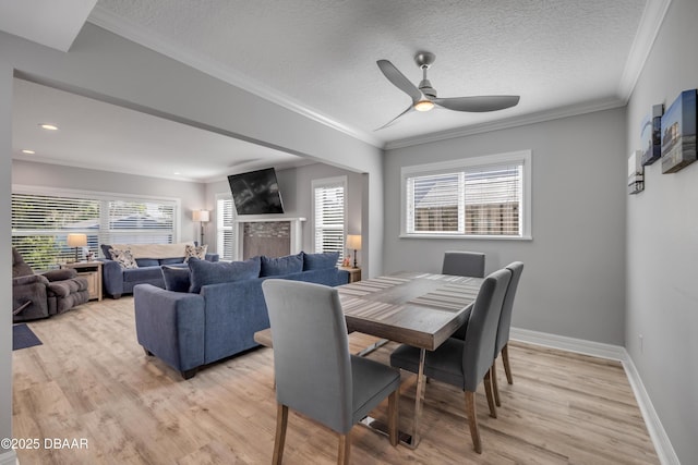 dining area with light wood-type flooring, crown molding, baseboards, and ceiling fan