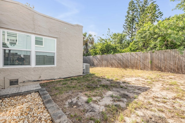 view of yard featuring fence and central AC