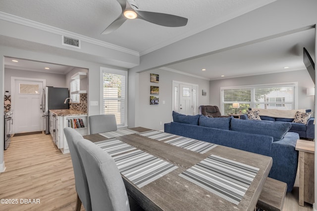 dining room featuring a healthy amount of sunlight, ceiling fan, light wood-type flooring, and visible vents