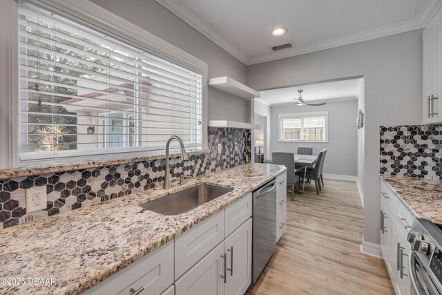 kitchen featuring crown molding, light stone countertops, a sink, stainless steel appliances, and tasteful backsplash