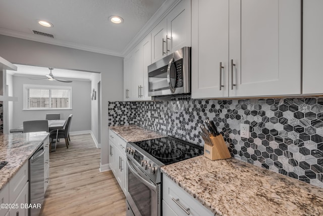 kitchen featuring crown molding, baseboards, light stone counters, light wood-style flooring, and stainless steel appliances