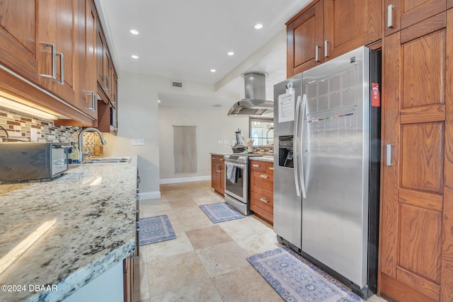 kitchen with island range hood, stainless steel appliances, a sink, backsplash, and light stone countertops