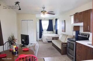 kitchen featuring ceiling fan, under cabinet range hood, electric range, open floor plan, and light countertops