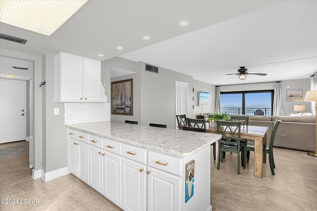 kitchen with white cabinets, ceiling fan, kitchen peninsula, and tasteful backsplash