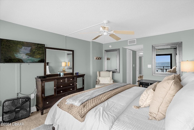 tiled bedroom featuring ceiling fan and a textured ceiling