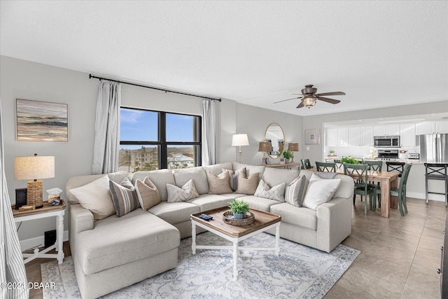 living room featuring a textured ceiling, light tile patterned floors, and ceiling fan