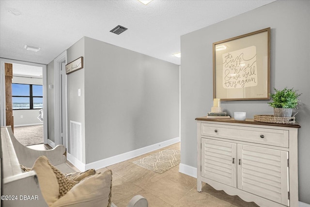 hallway featuring light tile patterned flooring and a textured ceiling