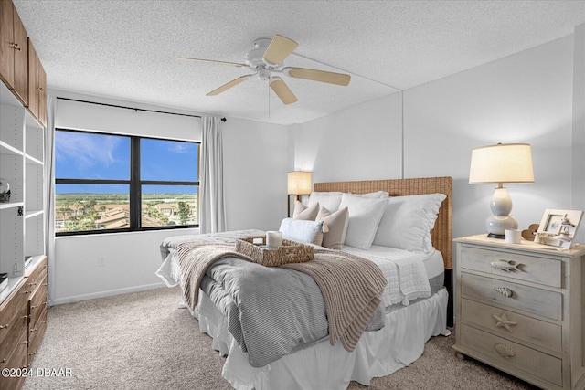 bedroom with a textured ceiling, light colored carpet, and ceiling fan