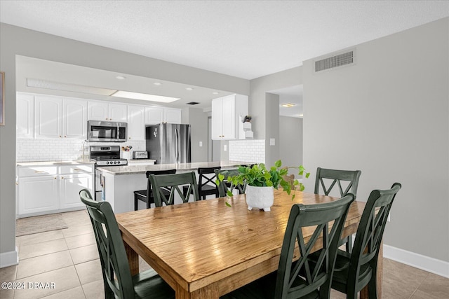 tiled dining space featuring a textured ceiling