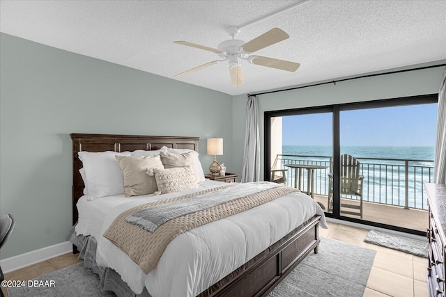 tiled bedroom featuring access to exterior, a textured ceiling, a water view, and ceiling fan