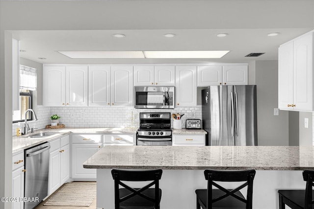 4445 S Atlantic Ave Unit 606, Ponce Inlet, FL 32127 - kitchen with stainless steel appliances, a sink, a breakfast bar, light stone countertops, and backsplash
