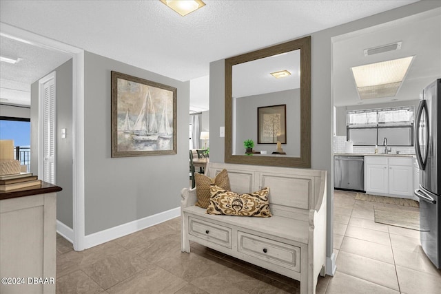 hallway with light tile patterned flooring, a textured ceiling, plenty of natural light, and sink