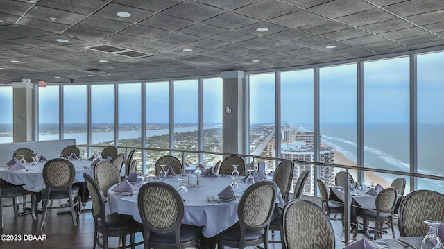 dining space with floor to ceiling windows, a water view, and hardwood / wood-style flooring