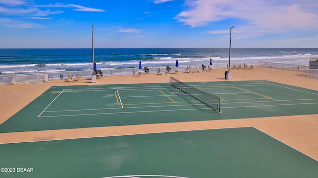 view of sport court with a water view and a view of the beach