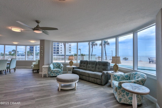 sunroom with ceiling fan, a water view, and a healthy amount of sunlight