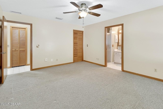 unfurnished bedroom featuring baseboards, visible vents, a ceiling fan, and light colored carpet