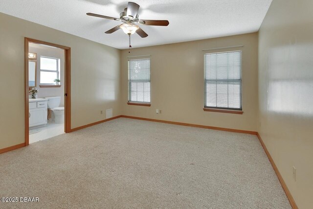 spare room featuring a wealth of natural light, ceiling fan, light carpet, and baseboards
