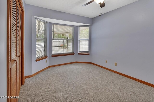 empty room featuring baseboards, a ceiling fan, and carpet