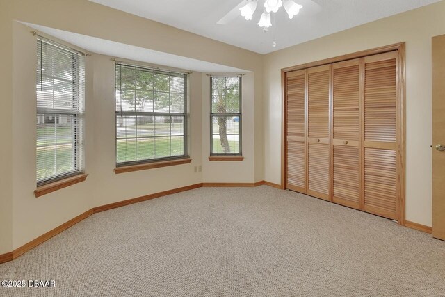 unfurnished bedroom featuring baseboards, a closet, a ceiling fan, and light colored carpet