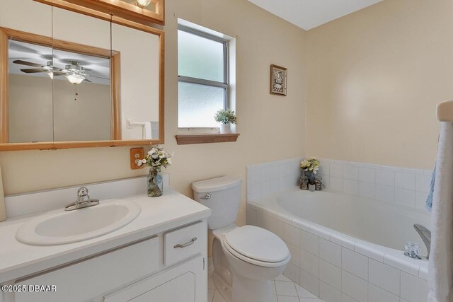 bathroom featuring tile patterned floors, toilet, vanity, a garden tub, and ceiling fan