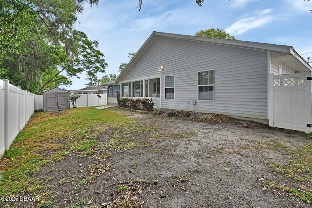rear view of house with a fenced backyard, an outdoor structure, and a storage shed
