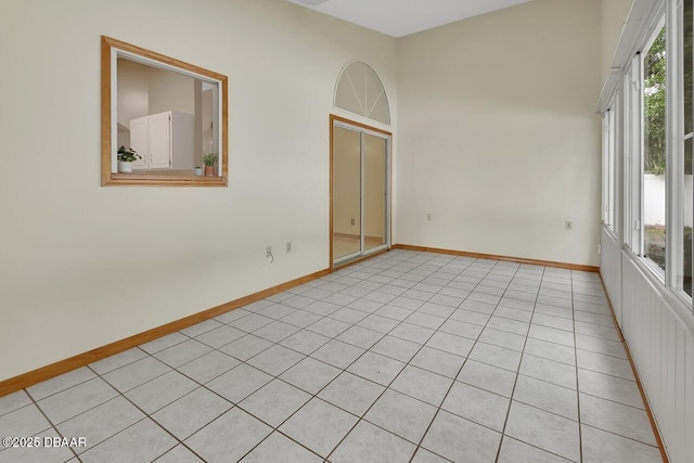 empty room featuring baseboards and light tile patterned flooring
