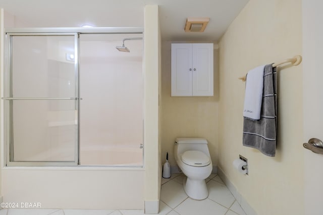 bathroom featuring toilet, tile patterned floors, and bath / shower combo with glass door