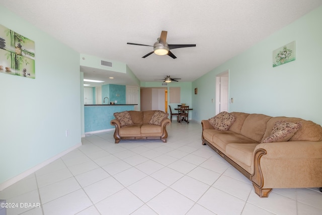 living room featuring light tile patterned flooring, a textured ceiling, ceiling fan, and sink