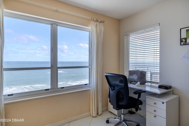 tiled home office with a textured ceiling and a water view