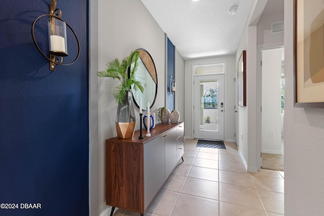 entryway with light tile patterned floors and a textured ceiling